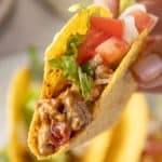 Rotel taco with a bite taken out of it being held up.