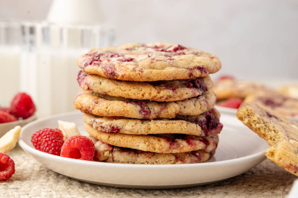 White Chocolate Raspberry Cookies on. a plate with a cup of milk in the background