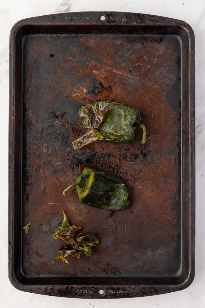 Charred poblano peppers on a sheet pan.