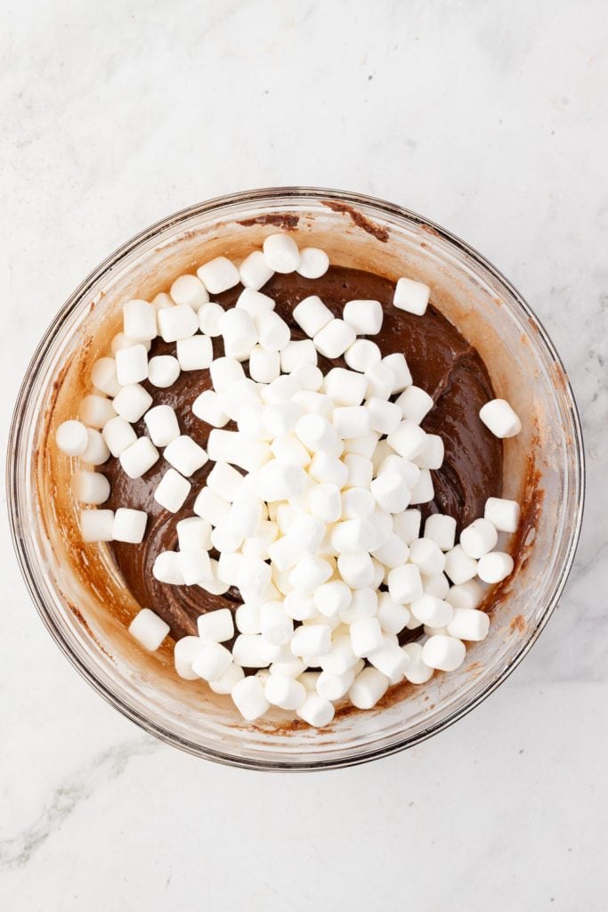 Melted hot fudge mix with mini marshmallows and a mixing bowl
