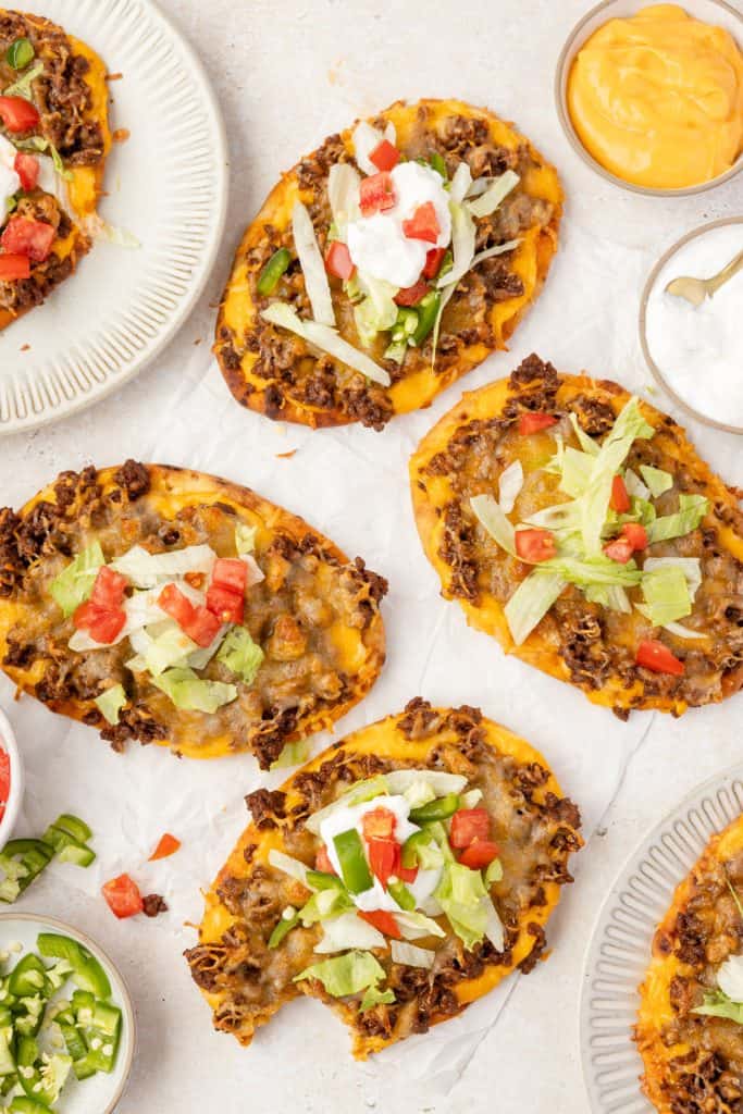 Naan Taco PizzaWeb049 Taco pizzas on a table with toppings.