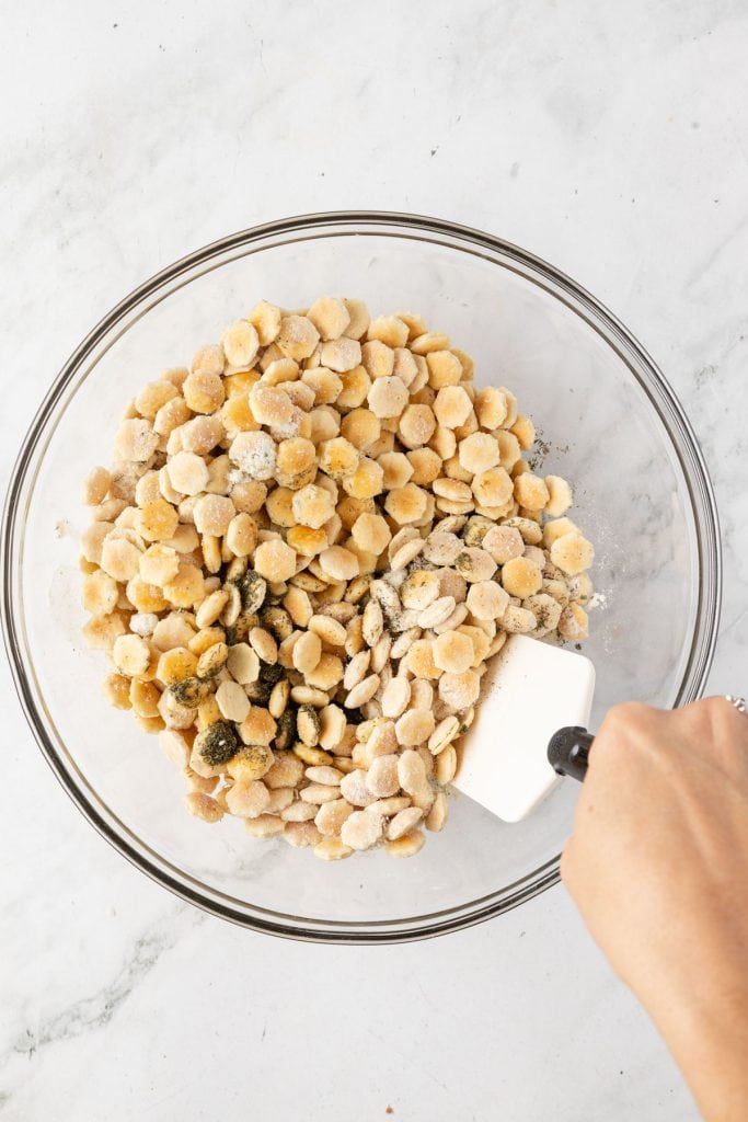 Stirring seasonings around on oyster crackers