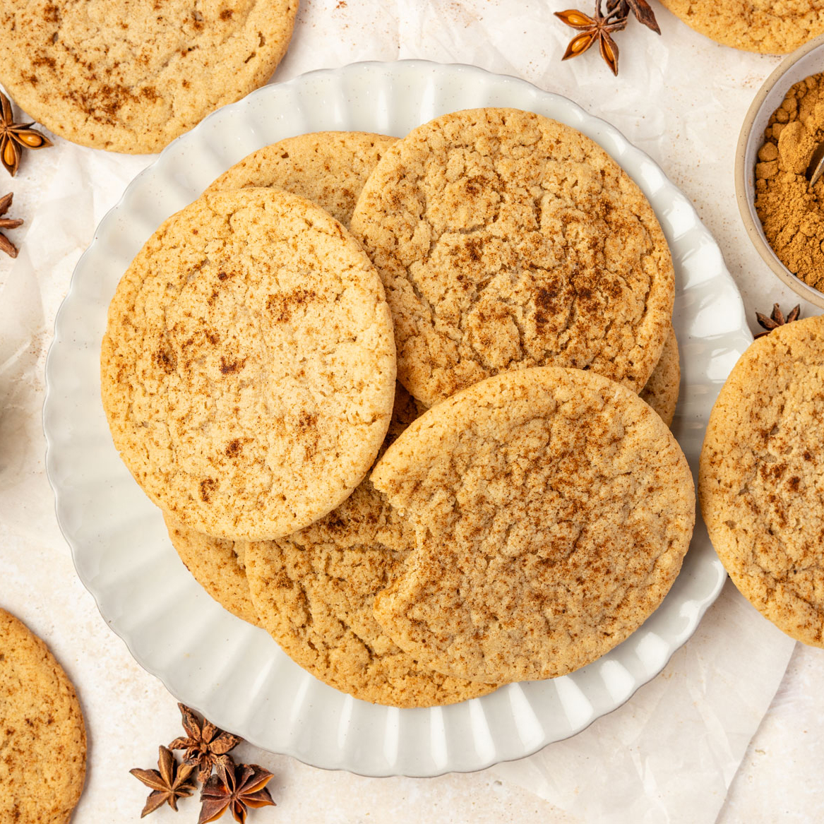 Pumpkin spice cookies on a plate plate with a bowl of pumpkin spice and spices around it and a baby pumpkin
