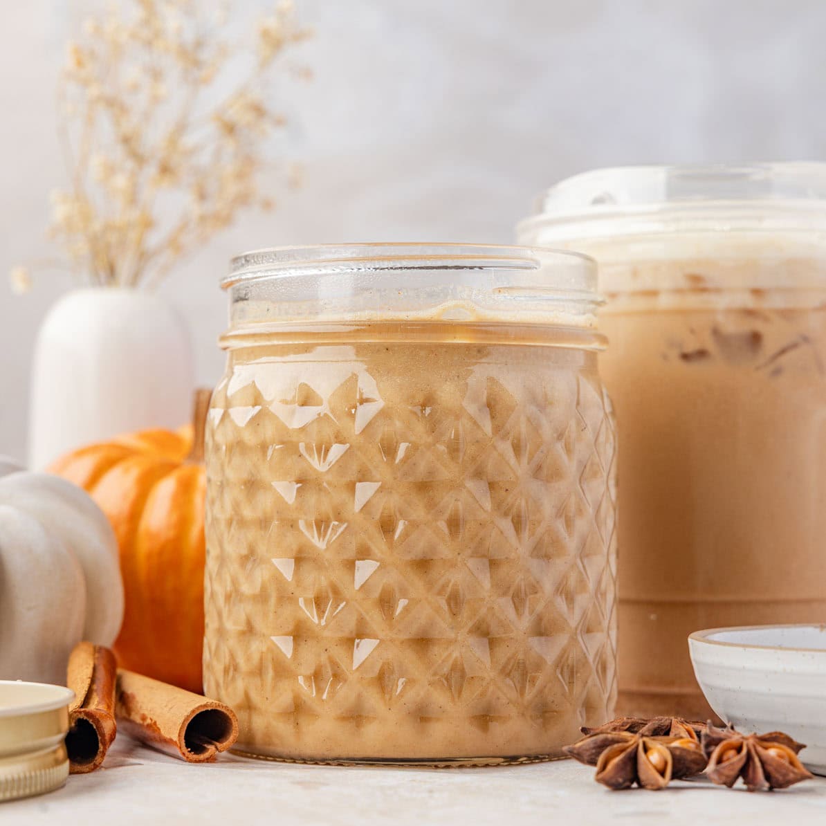 Pumpkin sauce in a mason jar with a latte in the background