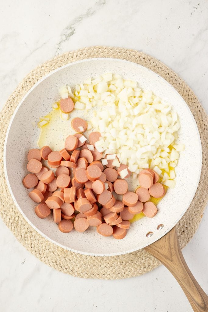 Onions and hotdog in a pan.