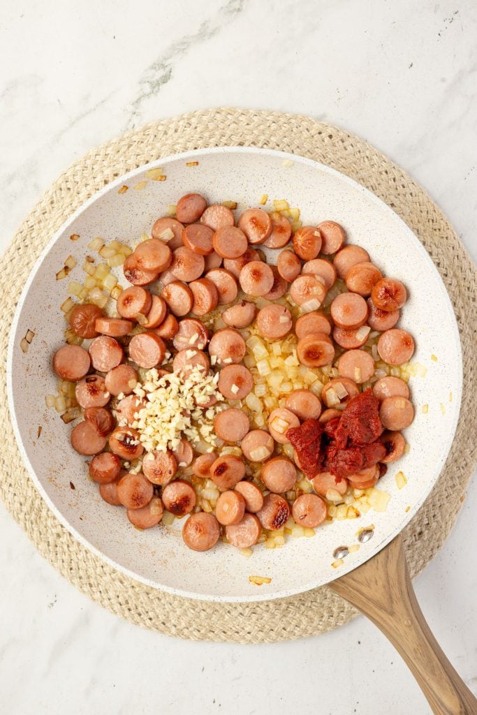 Hotdog, onions, garlic, tomato paste in a pan.