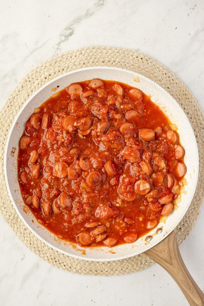Hotdog and tomato sauce in a pan.