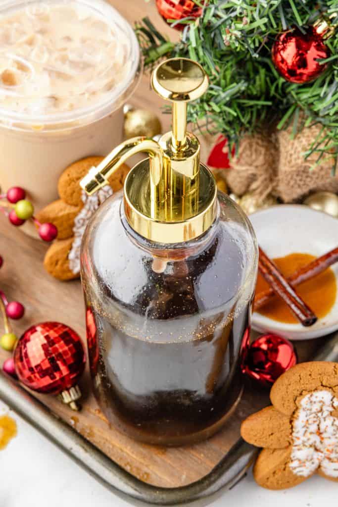 Gingerbread Simple SyrupWeb020 Gingerbread Simple Syrup in a container with a latte and Christmas decorations