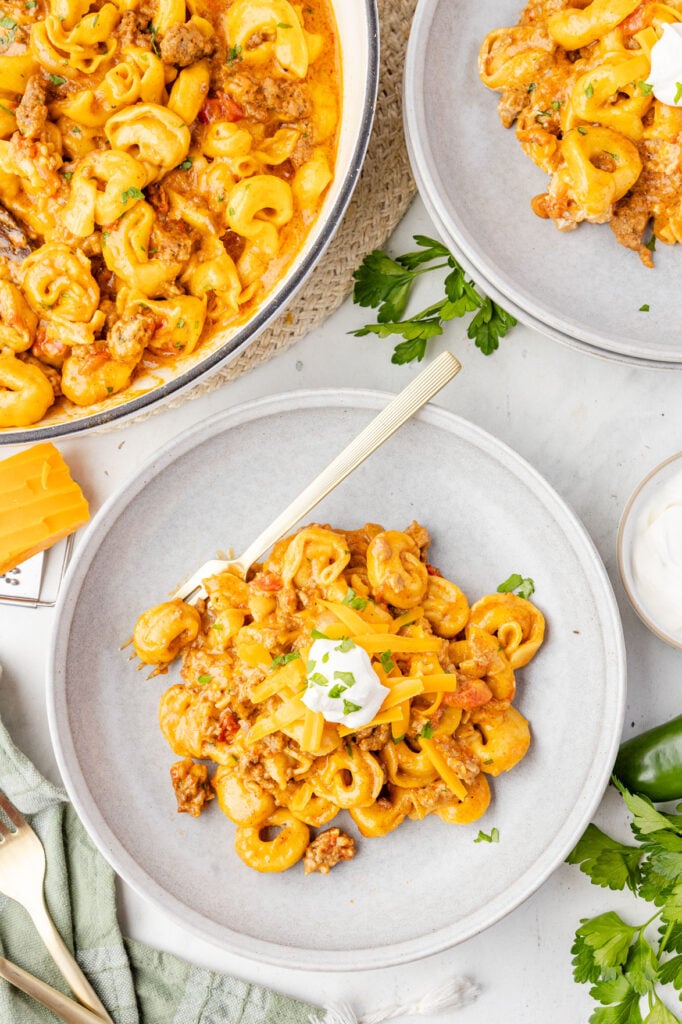 One Pot Taco TortelliniWeb034 Taco tortellini in a bowl with sour cream on top of it and a fork in the bowl.