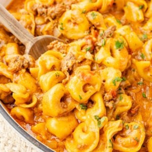 Up close image of taco tortellini with a wooden spoon inside of a skillet.