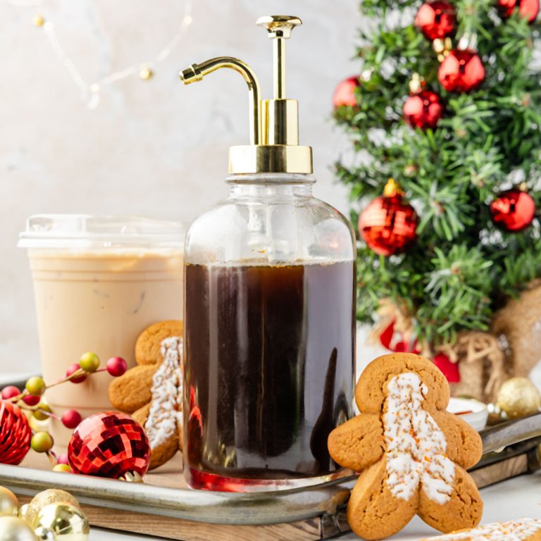 Gingerbread Simple Syrup in a container with a latte and Christmas decorations