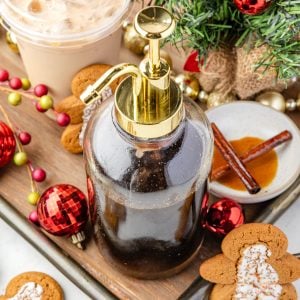 Gingerbread Simple Syrup in a container with a latte and Christmas decorations