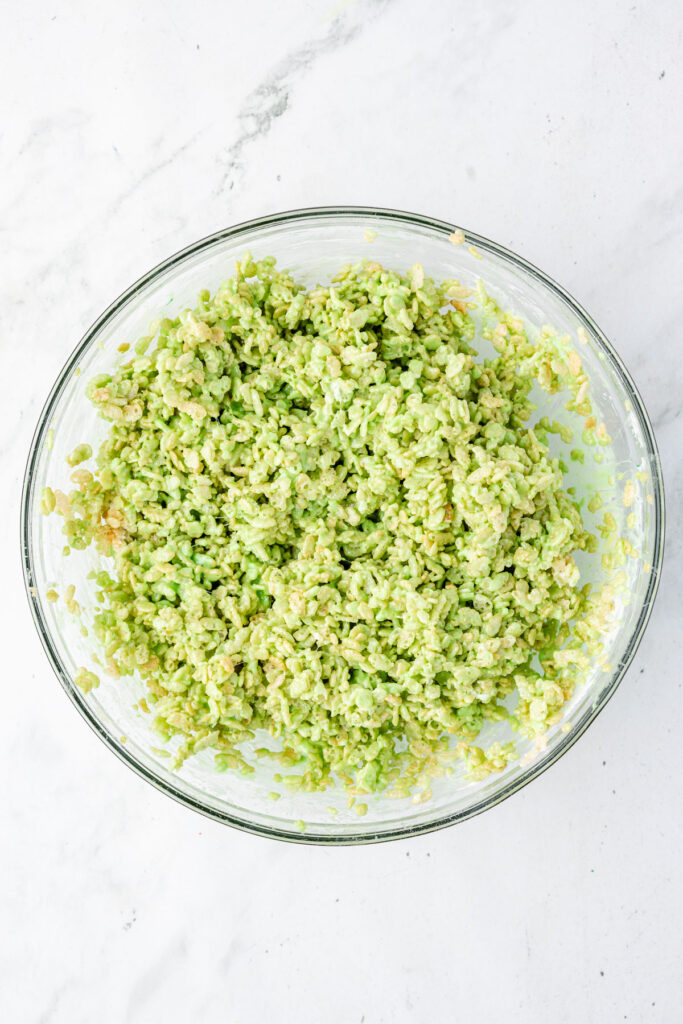 Rice crispies, covered in green marshmallows that have been melted in a large mixing bowl