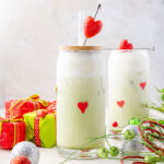 Grinch Matcha latte in a cup with grinch holiday decorations around it