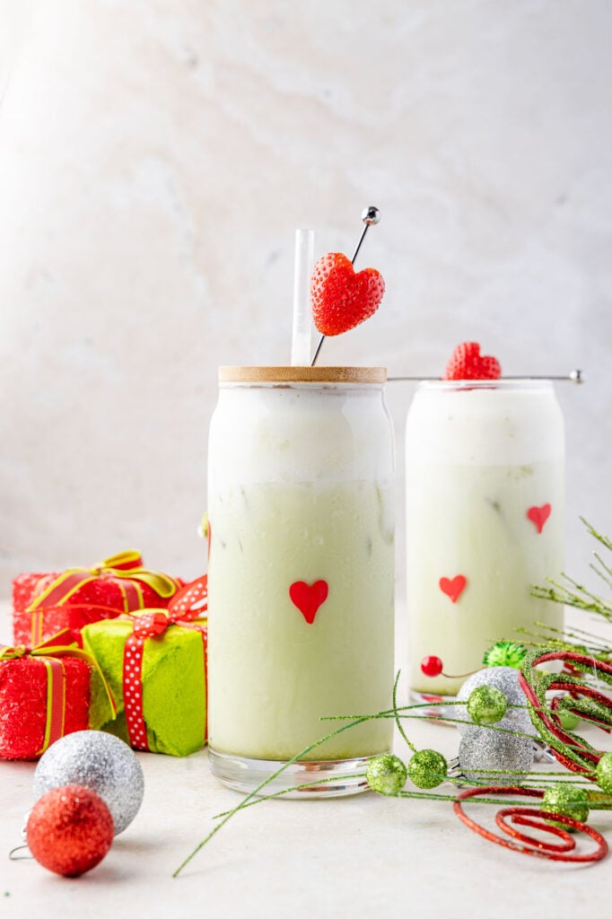 Iced grinch Matcha latte on a surface with lots of grinch decorations