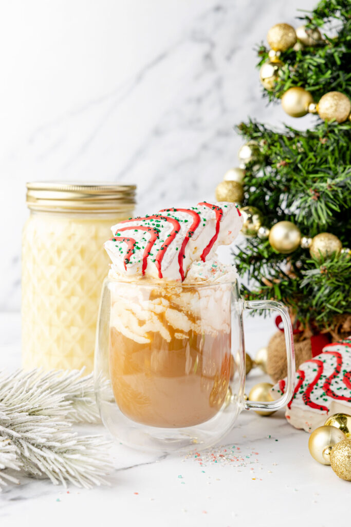 Cup of coffee with Christmas tree, coffee creamer topped with a little Debbie Christmas tree