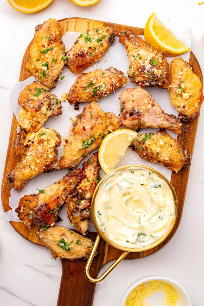 Air Fryer Garlic Parmesan Wings on a cutting board with a dip.