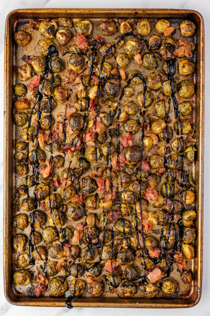 Brussels sprouts coated in a balsamic glaze on a sheet pan.
