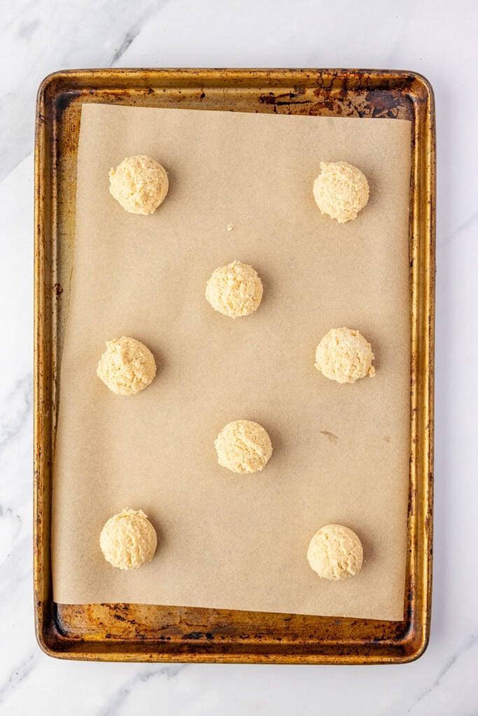 Raw chocolate chipless cookies on a sheet pan with parchment paper.
