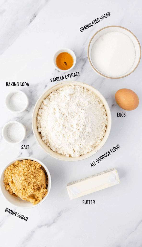 All the ingredients to make chocolate chipless cookies in small ingredient bowls on a marble surface.