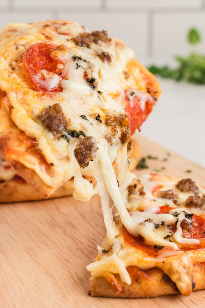 Cheese pull of a naan flatbread pizza.