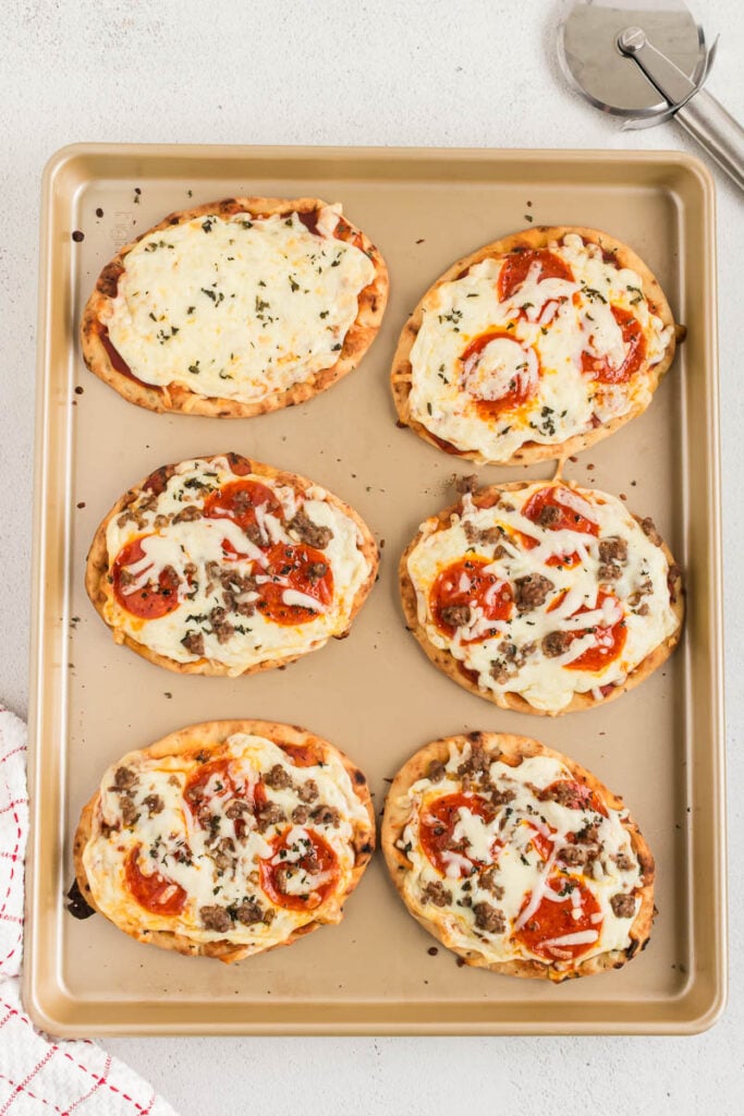Cooked naan flatbread pizza on a sheet pan.