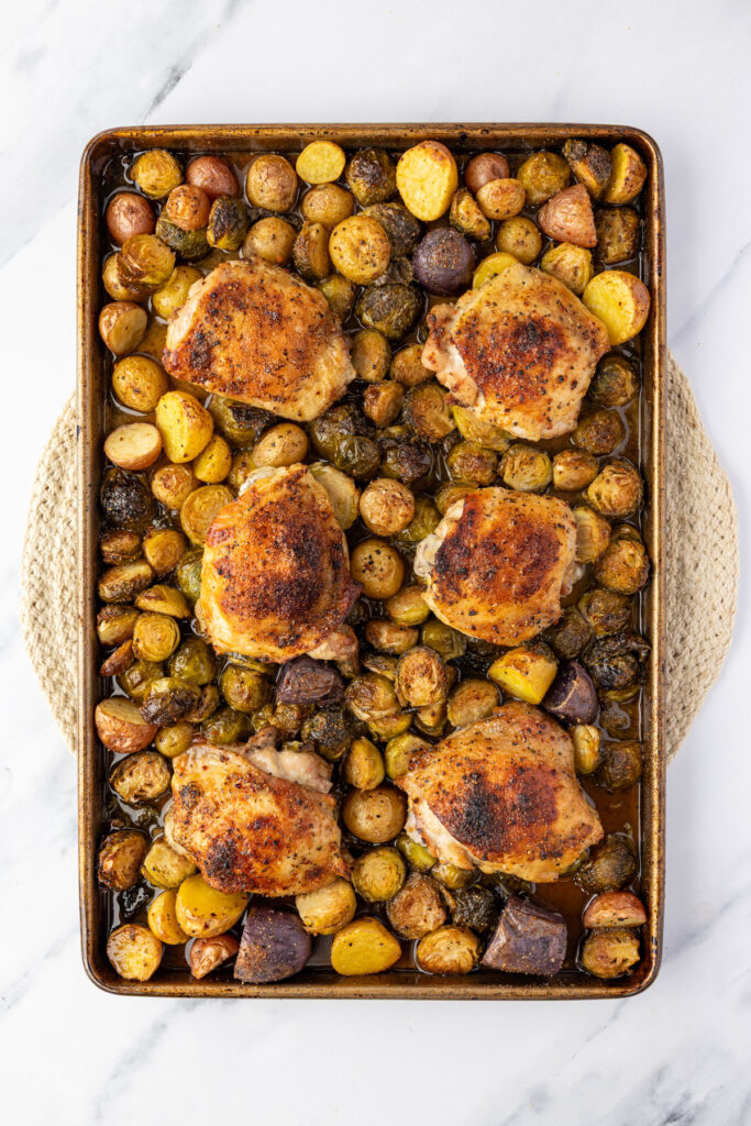 Cooked sheet pan, chicken thighs on a sheet pan with potatoes and brussels sprouts