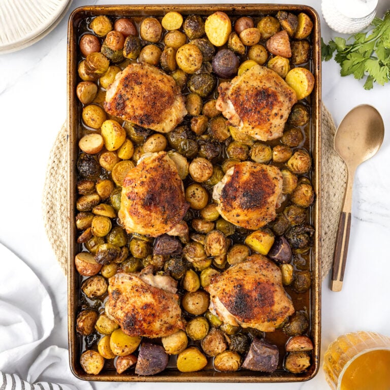 Sheet pan, chicken thighs cooked out of the oven with roasted brussels sprouts and potatoes