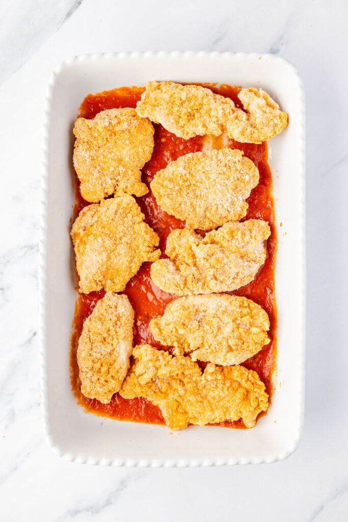 Sauce and a casserole pan topped with chicken strips