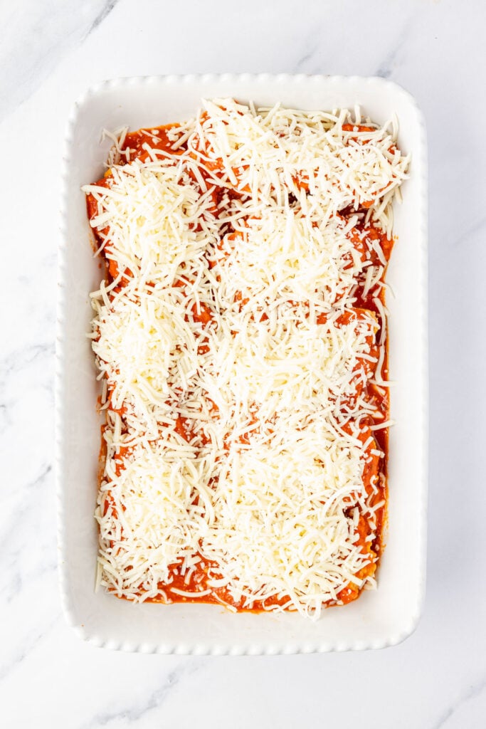 Cheese on top of chicken strips in a casserole pan