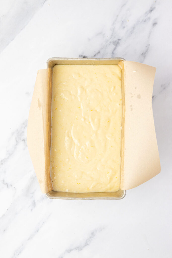 Lemon loaf batter in a pan with parchment paper.