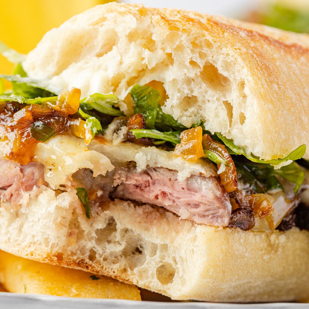 Close up of a steak sandwich with one bite taken out of it