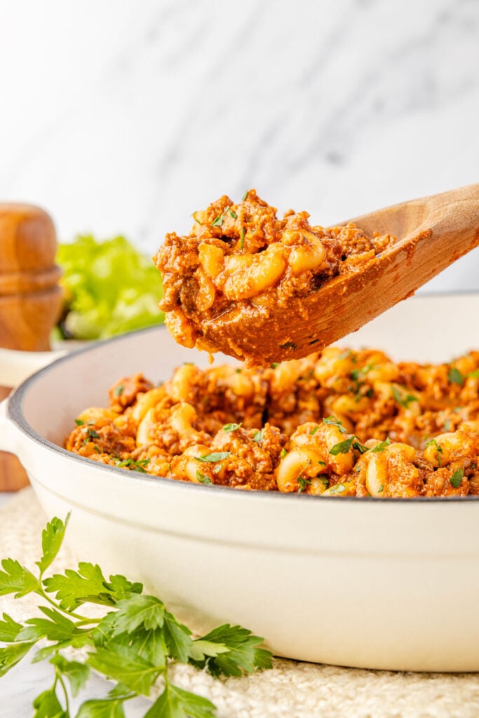 Sloppy Joe pasta in a pan scooping out some of the pasta.