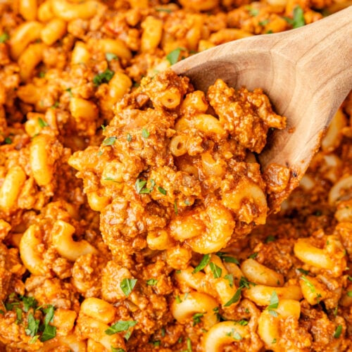 Handful of sloppy Joe pasta with a wooden spoon scooping
