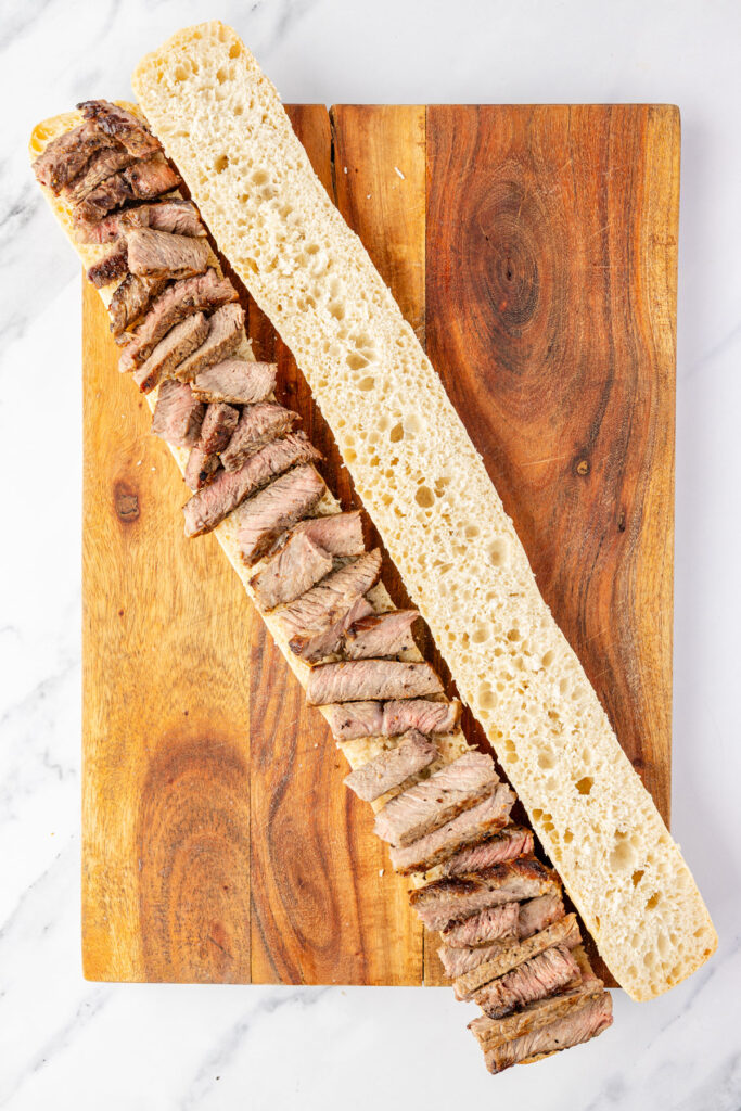 Baguette cut open on a cutting board topped with a st