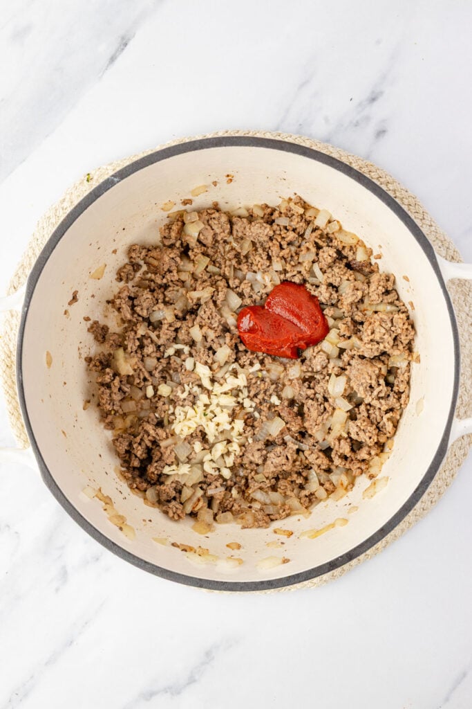 Cooked meat and onions and tomato paste and garlic in a pot