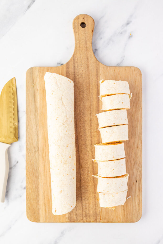 Cutting pinwheels into 1 inch pieces on a cutting board