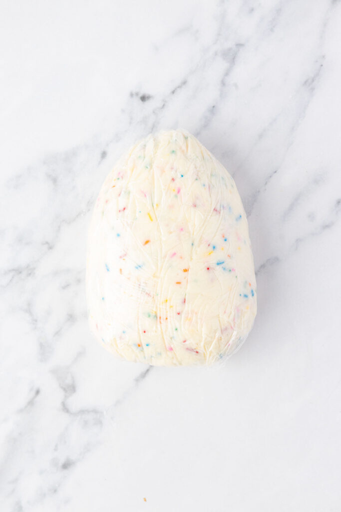 Easter cheesecake ball being shaped in saran wrap