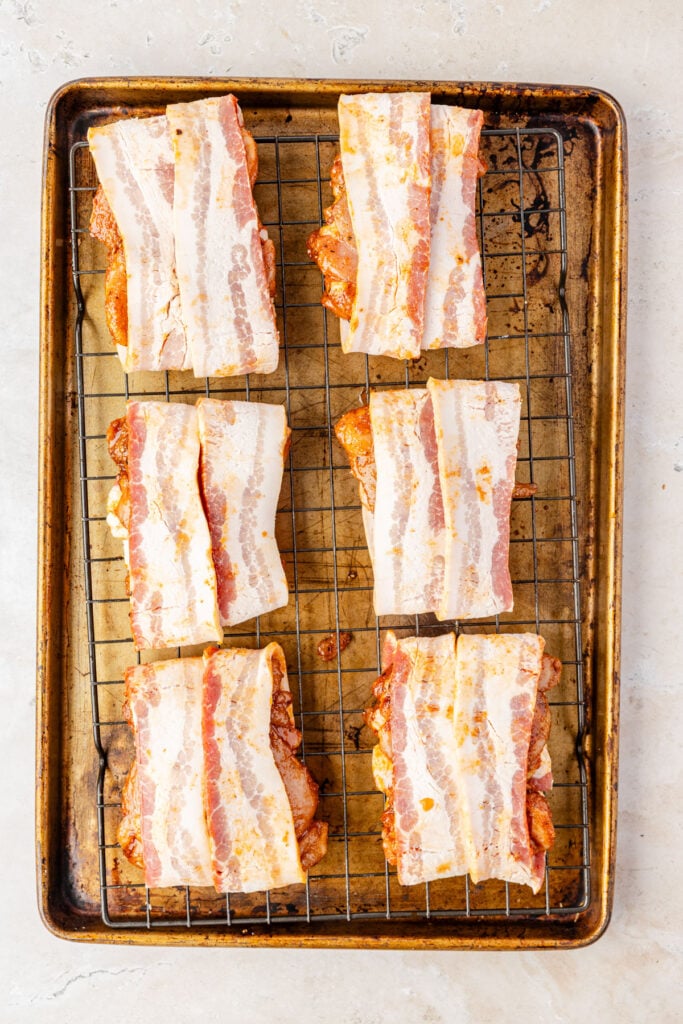 raw Bacon Wrapped Chicken Thighs on a sheetpan