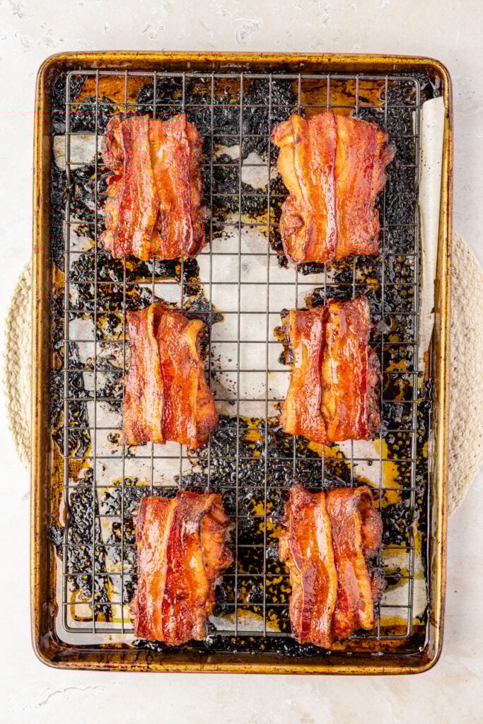 cooked Bacon Wrapped Chicken Thighs on a cooling rack