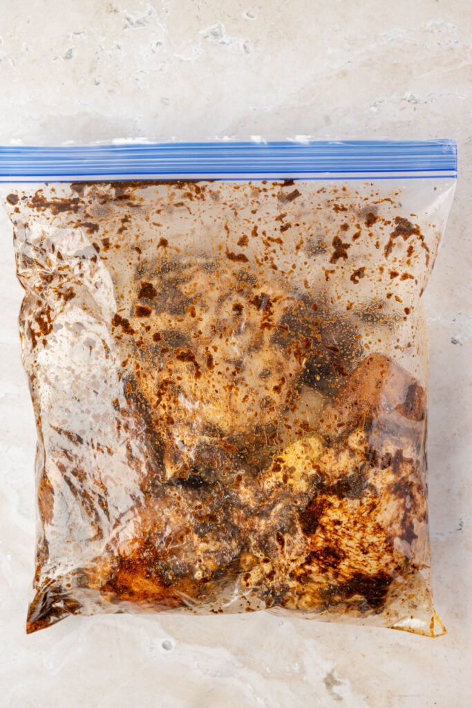Ziploc bag, full of chicken, spices, jerk, seasoning, paste, oil, and browning seasoning for jerk chicken