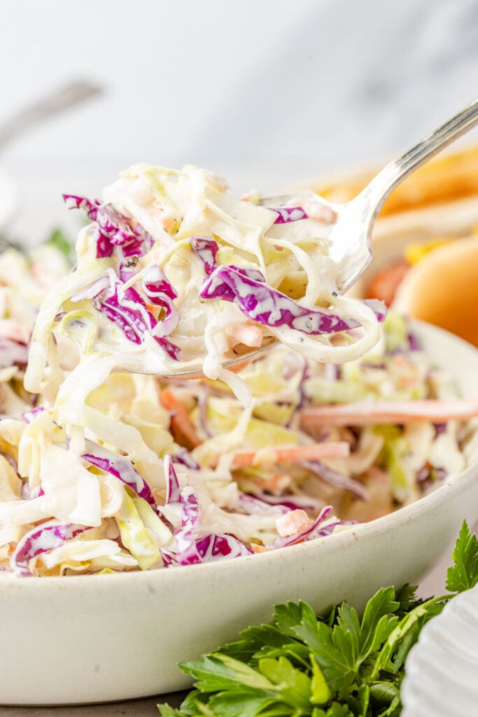 A spoon scooping Creamy Greek Yogurt Coleslaw