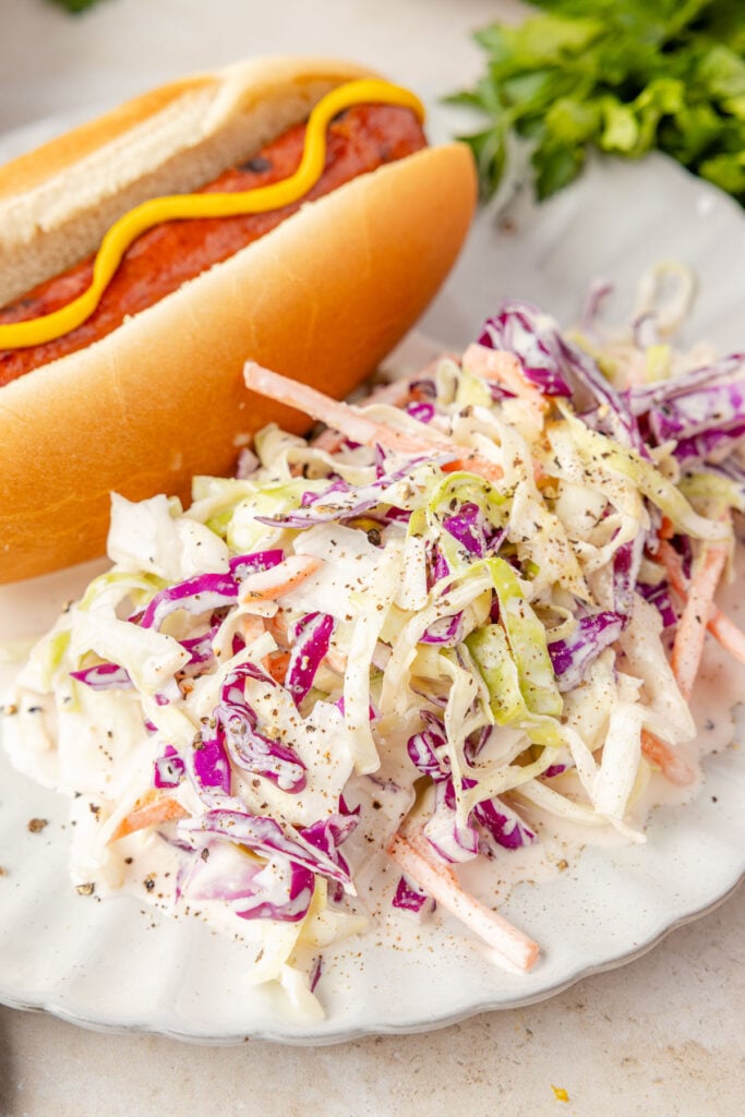 Close-up of Creamy Greek Yogurt Coleslaw on a plate with a hotdog