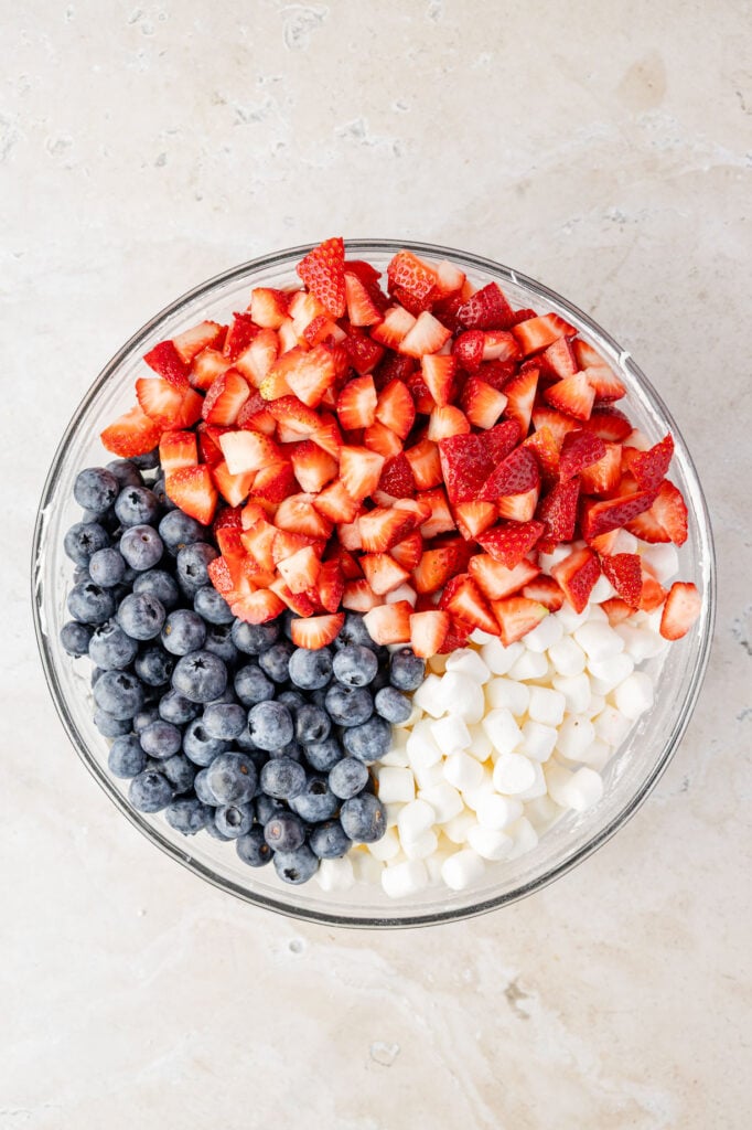 Mini marshmallows, strawberries, and blueberries in a mixing bowl