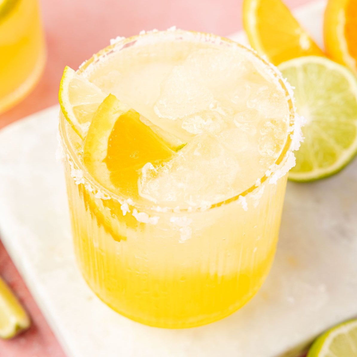 Virgin Margarita (Margarita Mocktail) in a glass with limea and oranges around it.