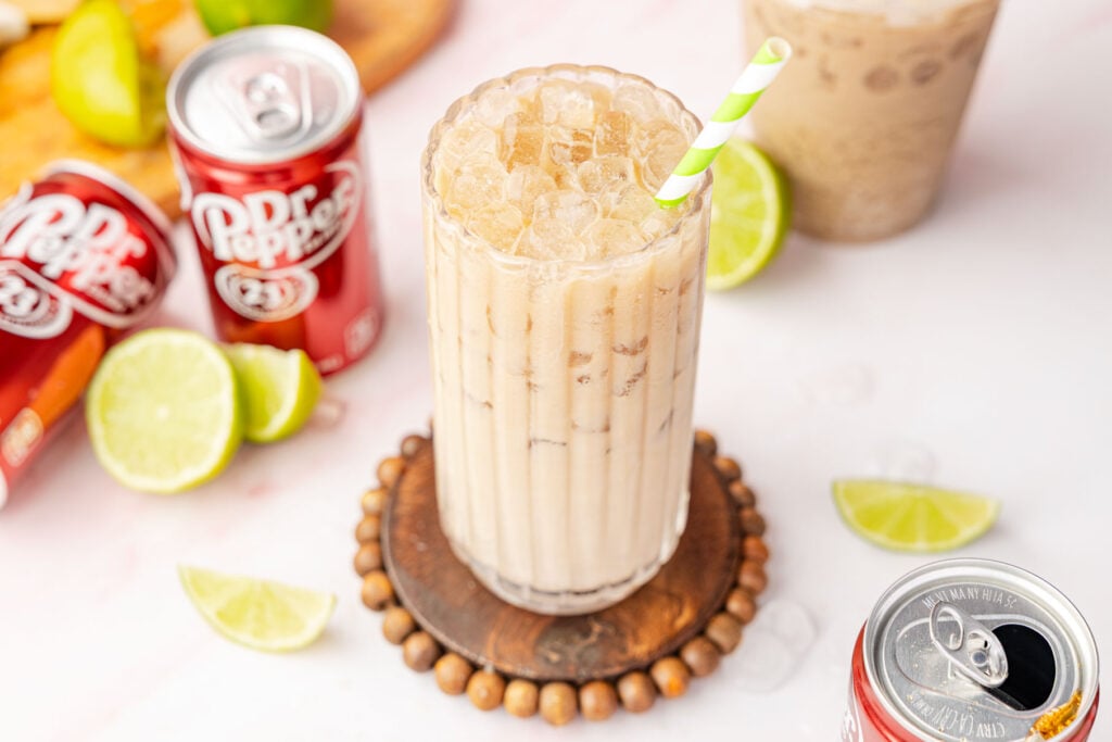 Dirty Dr Pepper in a glass with limes and a can of the dr pepper