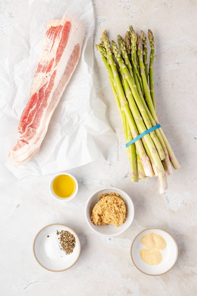Ingredients to make bacon wrapped asparagus on a stone background