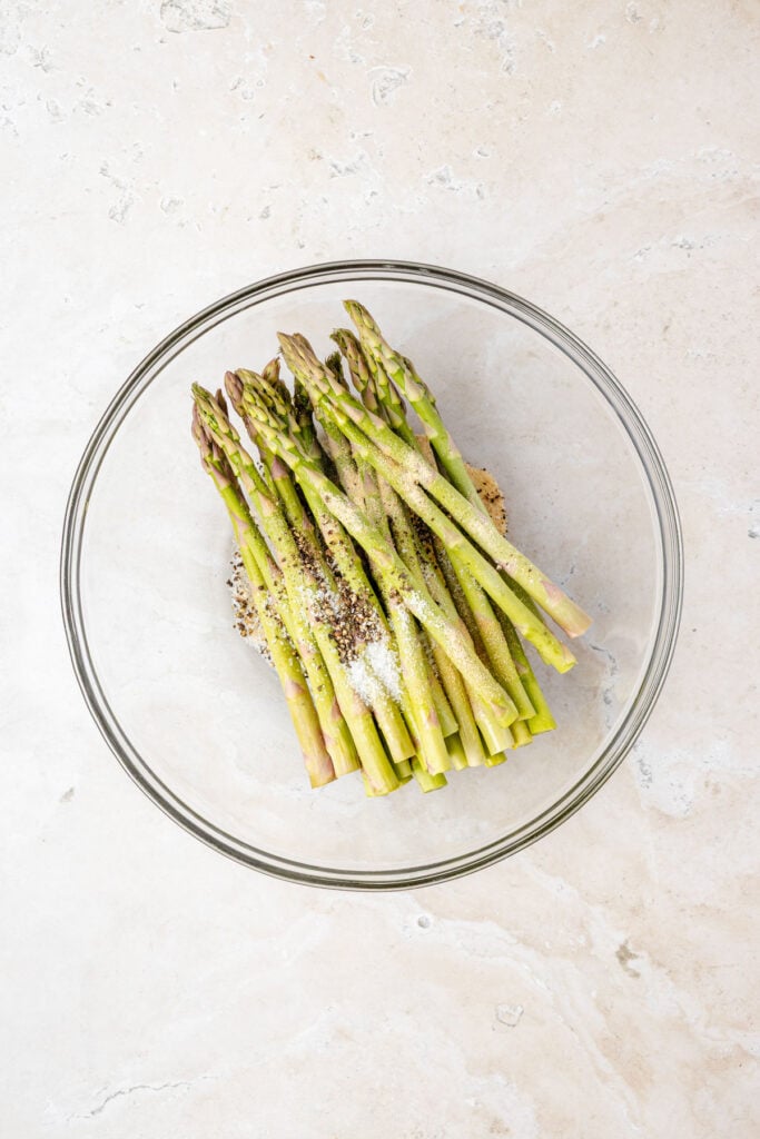Asparagus in a mixing bowl with spices
