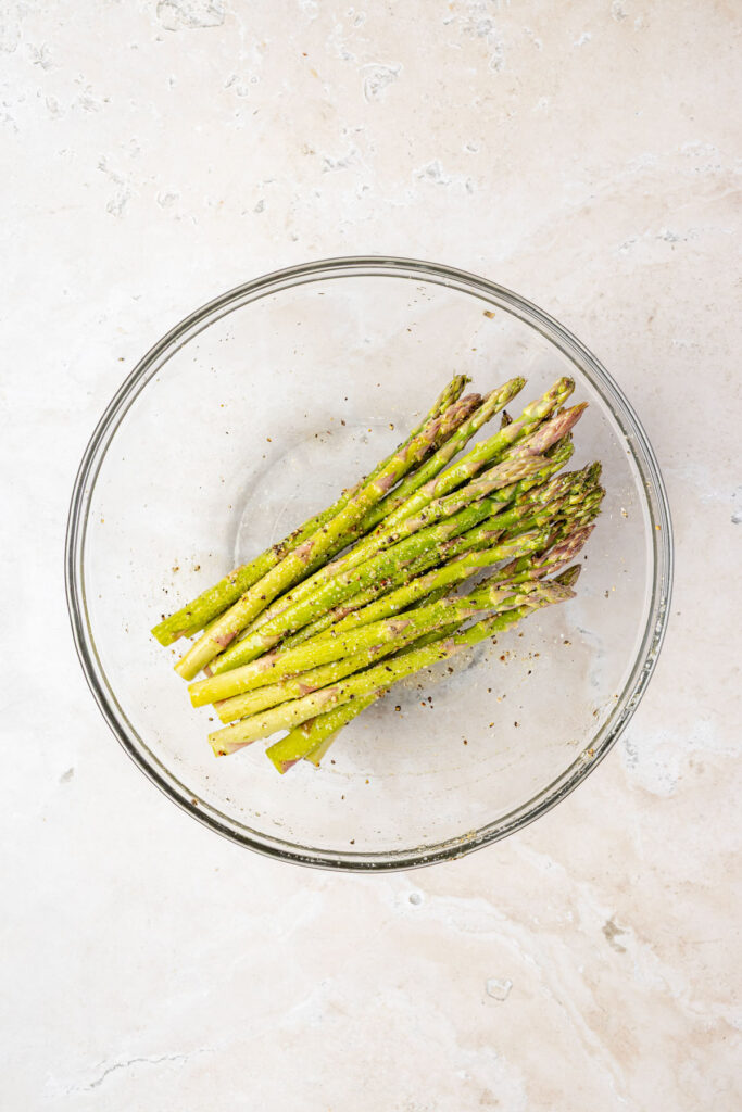 Seasoned asparagus in a mixing bowl