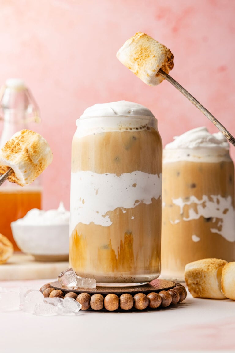 Marshmallow fluff lined cup for twisted marshmallow latte with marshmallows in the background